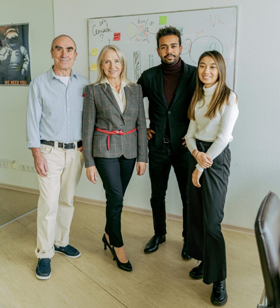 A diverse team of business professionals standing in an office with a whiteboard.